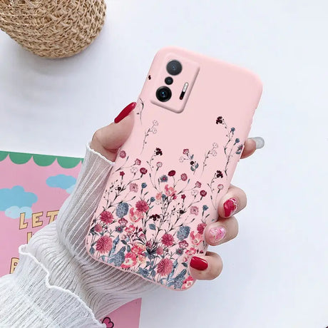 a woman holding a pink phone case with flowers on it