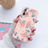 a woman holding a phone case with a floral pattern