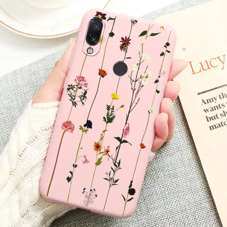 a woman holding a pink phone case with flowers on it