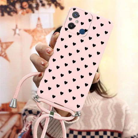 a woman holding a pink phone case with black hearts on it