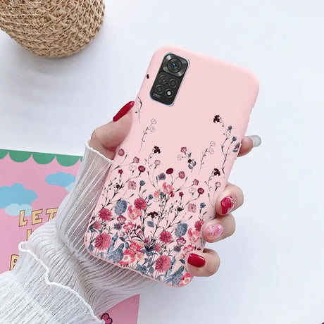 a woman holding a pink phone case with flowers on it