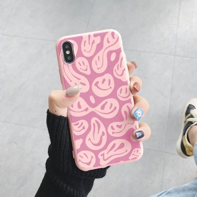 a woman holding a pink phone case with a pink pattern