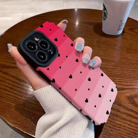 a woman holding a pink phone case with hearts on it