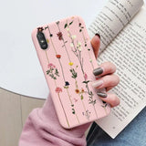 a woman holding a pink phone case with flowers on it