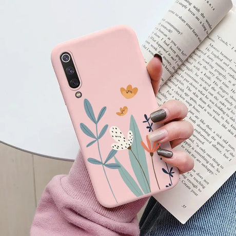 a woman holding a pink phone case with a flower design