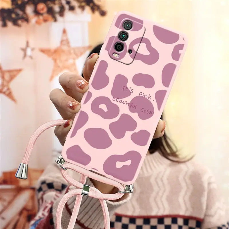 a woman holding a pink phone case with a pink leopard print