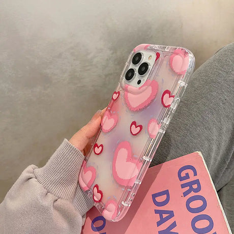 a woman holding a pink phone case with hearts on it