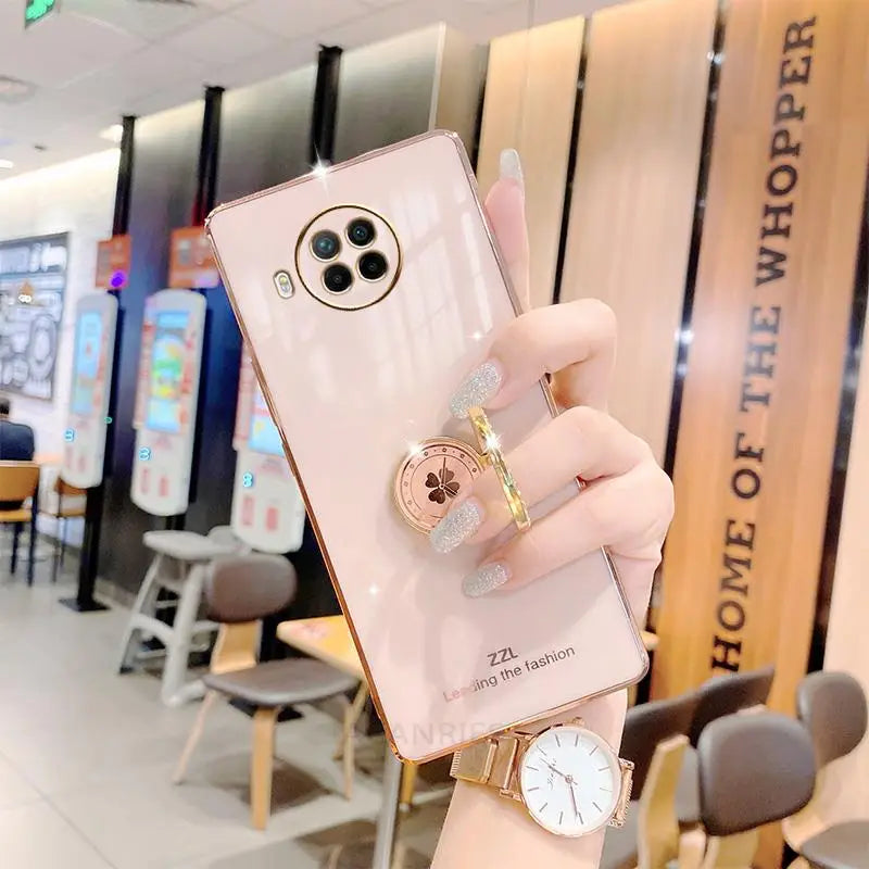 a woman holding a pink phone case with a watch on it
