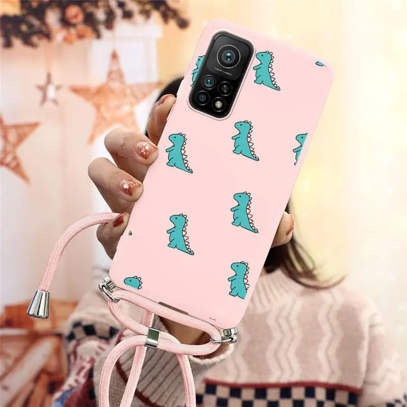 a girl holding a pink phone case with a green dinosaur print