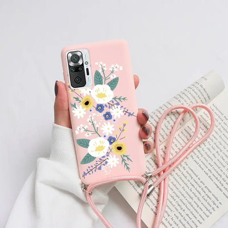 a woman holding a pink phone case with flowers on it