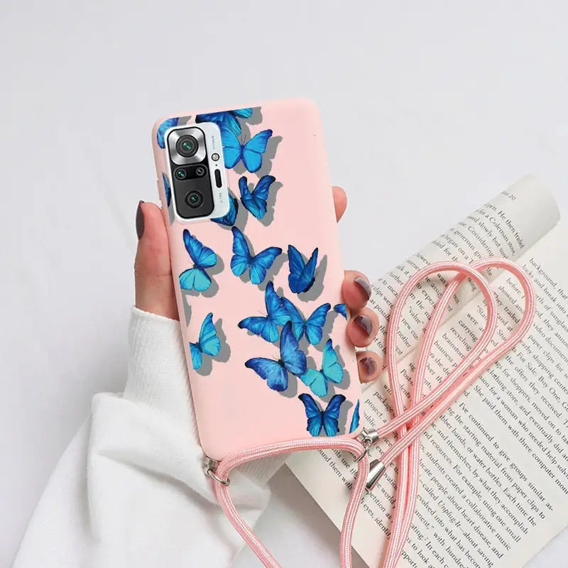 a woman holding a pink phone case with blue butterflies on it