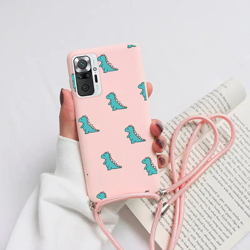 a woman holding a pink phone case with a green dinosaur print