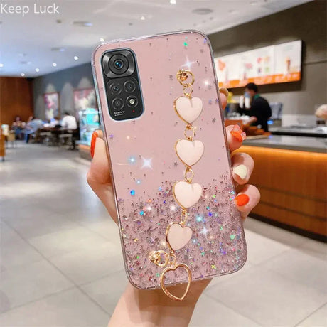 a woman holding a pink phone case with heart charms