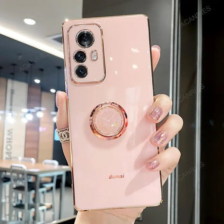 a woman holding a pink phone case with a ring on it