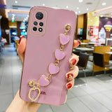 a woman holding a pink phone case with heart charms