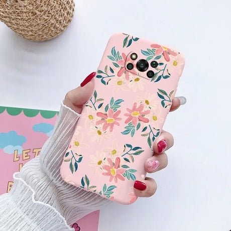 a woman holding a pink phone case with flowers on it