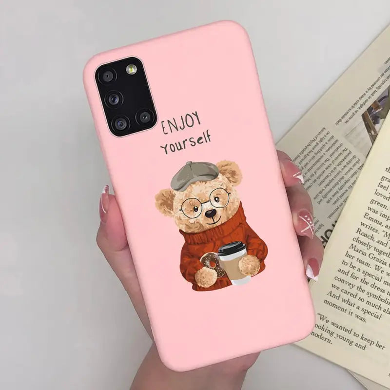 a woman holding a pink phone case with a teddy bear