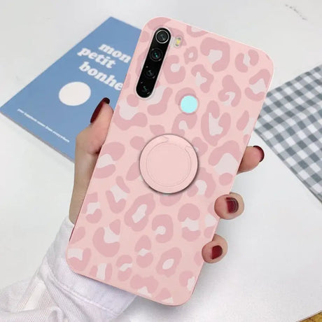 a woman holding a pink phone case with a pink leopard print