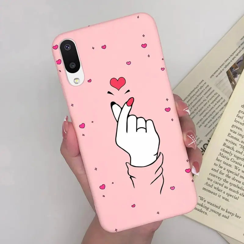 a woman holding a pink phone case with a heart on it