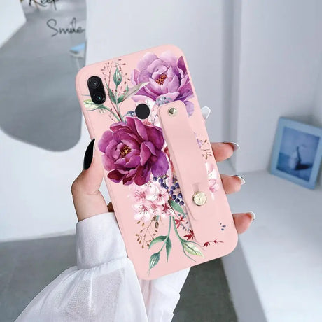 a woman holding a pink phone case with flowers on it