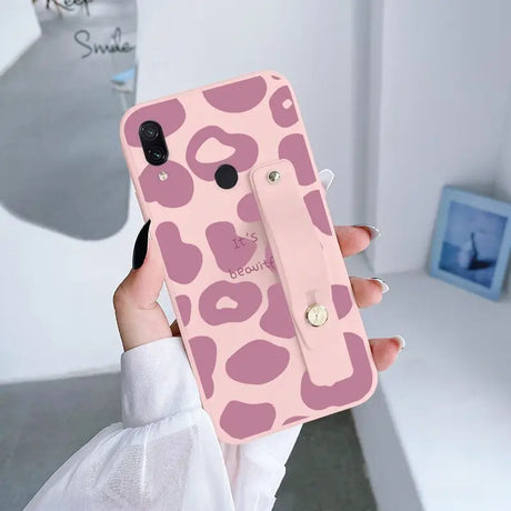 a woman holding up a pink phone case