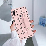 a woman holding a pink phone case with a grid pattern