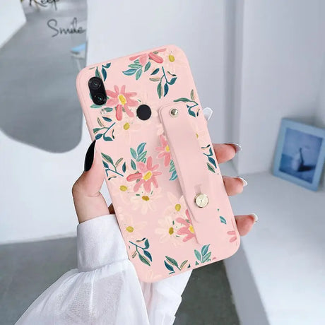 a woman holding a pink phone case with flowers on it