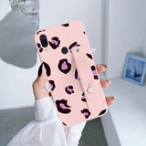 a woman holding a pink phone case with a pink leopard print