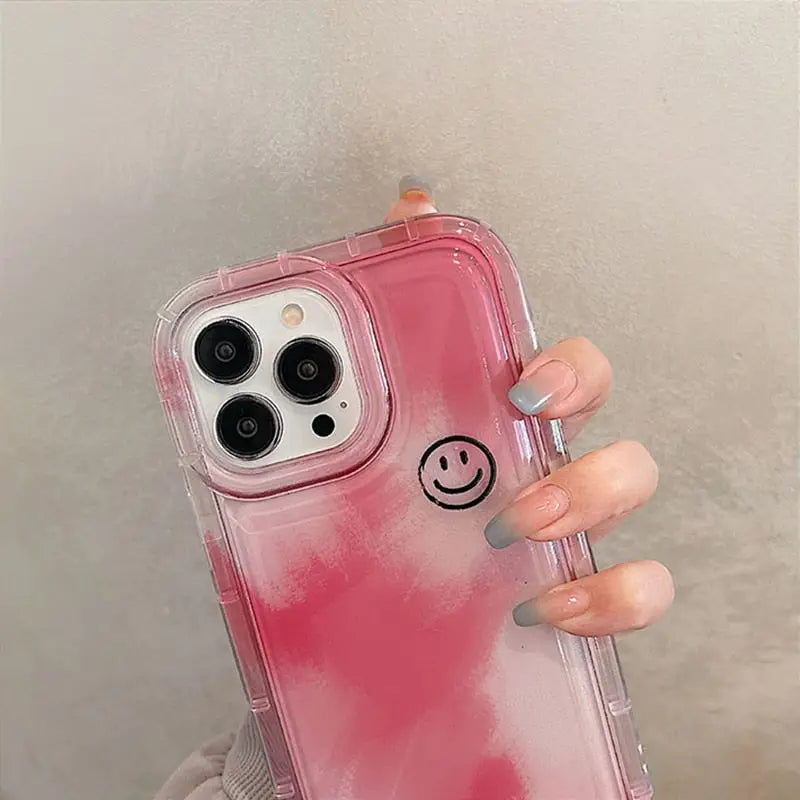 a woman holding a pink phone case with a smiley face on it