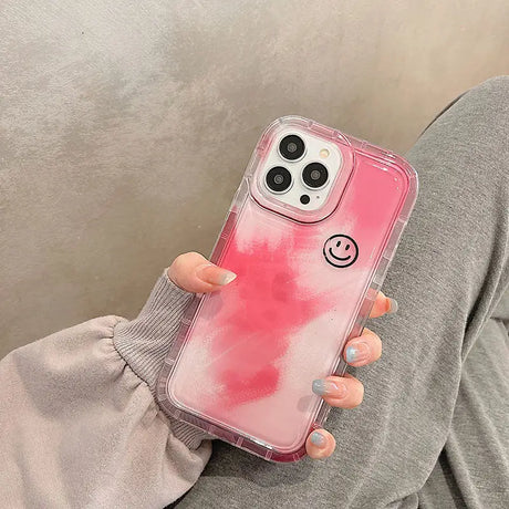 a woman holding a pink phone case with a smiley face on it