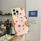 a woman holding a pink and yellow polka phone case