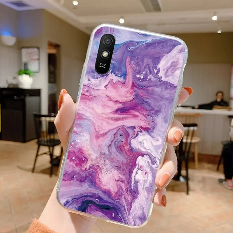 a woman holding up a purple and blue marble phone case