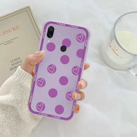 a woman holding a purple phone case with hearts on it