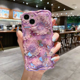 a woman holding up a purple phone case with flowers on it