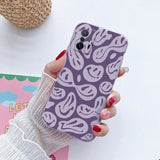 a woman holding a phone case with a purple and white pattern