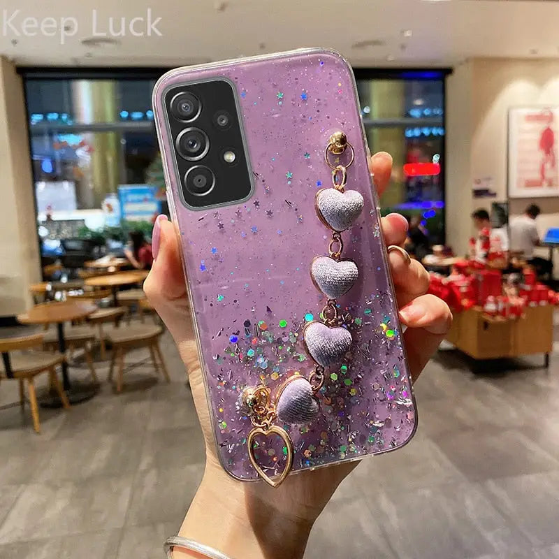 a purple phone case with a purple glitter and gold charms