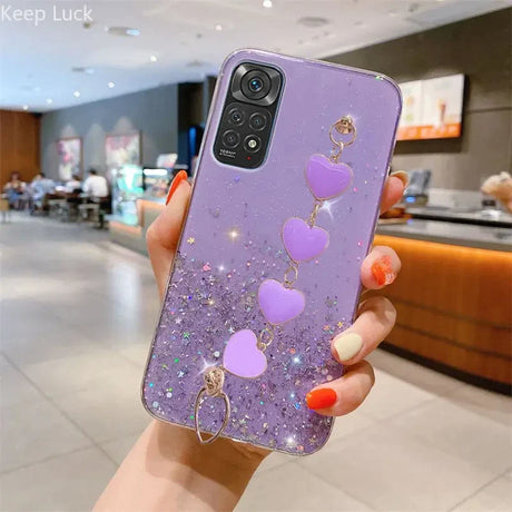 a woman holding a purple phone case with heart charms