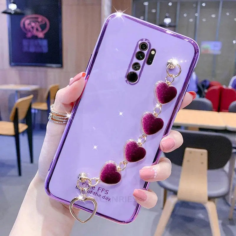a woman holding a purple phone case with heart charms