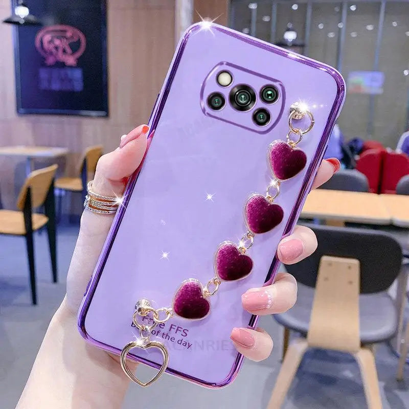 a woman holding a purple phone case with heart charms