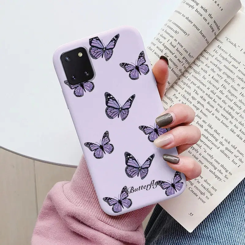 a woman holding a book and a purple butterfly phone case