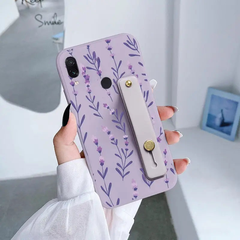 a woman holding a purple phone case with flowers on it