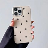a woman holding a white and black polka dot phone case