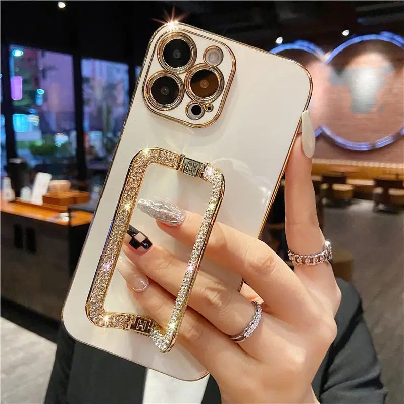 a woman holding a white iphone case with a gold ring on it