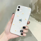 someone holding a white iphone case with a daisy design
