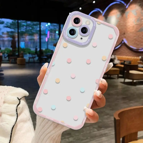 a woman holding up a white phone case with polka dots