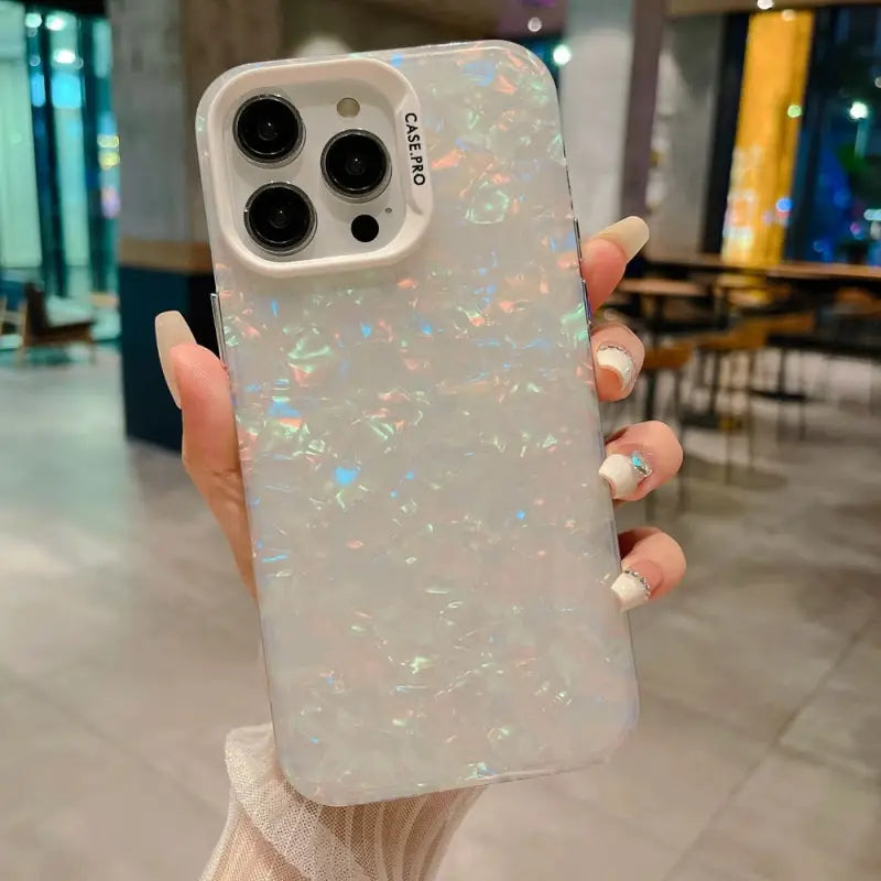 a woman holding up a white iphone case with irl glitter