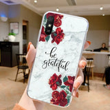 a woman holding up a marble phone case with red roses on it