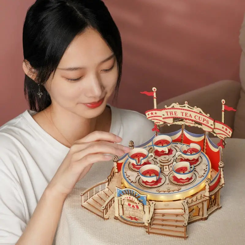 a woman holding a wooden model of a circus