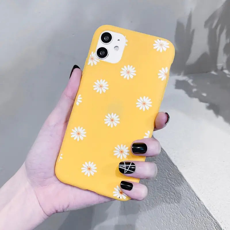 a woman holding a yellow phone case with white flowers on it
