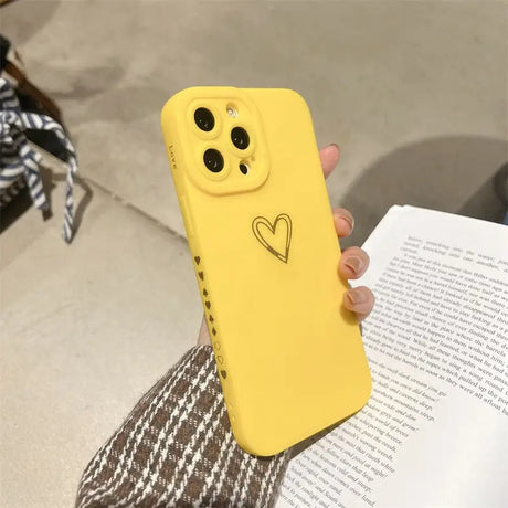 a woman holding a yellow phone case with a heart on it